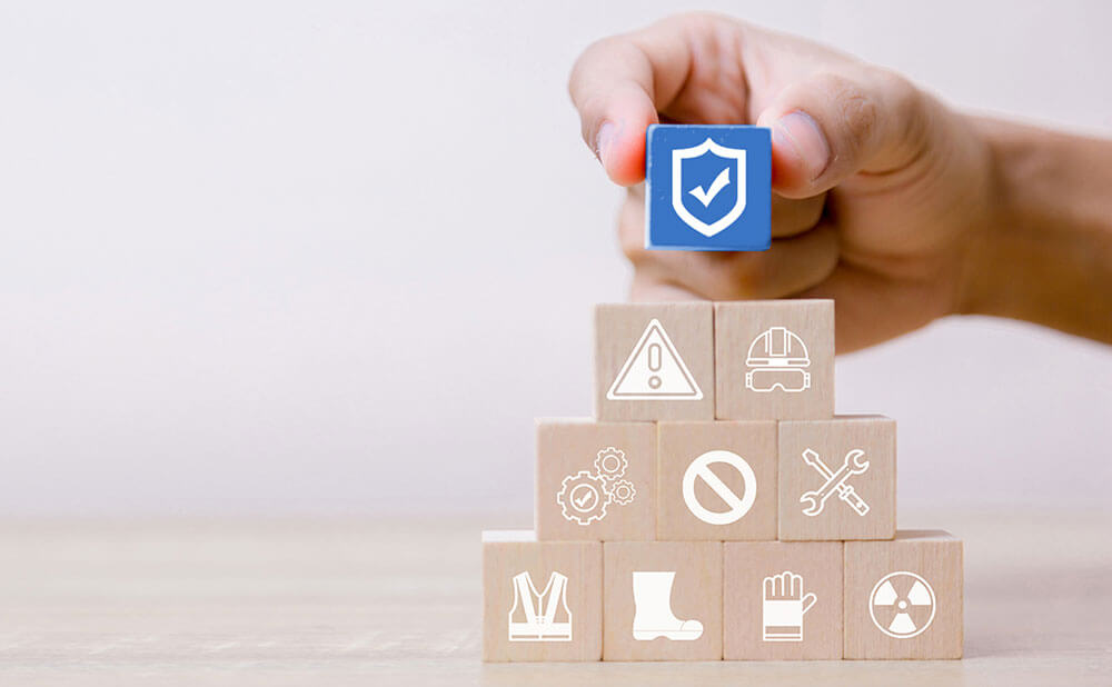 Connaissances santé sécurité Plusieurs cubes les uns sur les autres forment une petite pyramide. Chaque cube a une illustration d\'un thème sur la sécurité. Celui tout en haut est le seul coloré et c\'est le logo de la sécurité.