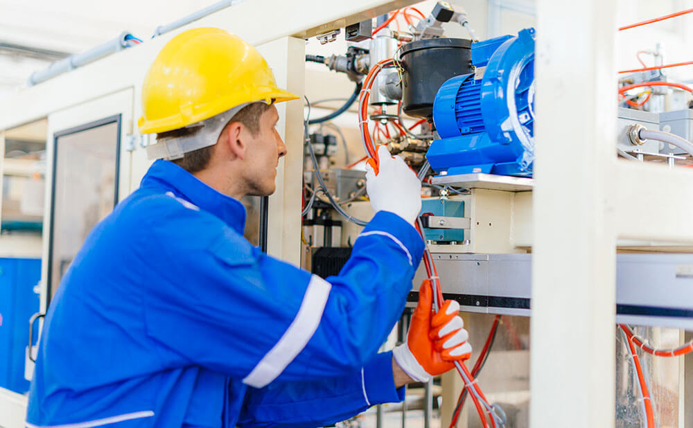 Homme en tenue de travaille de protection qui fait de la maintenance industrielle