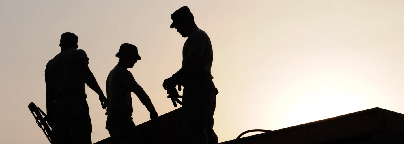 trois hommes travaillant sur un toit en fin de journée