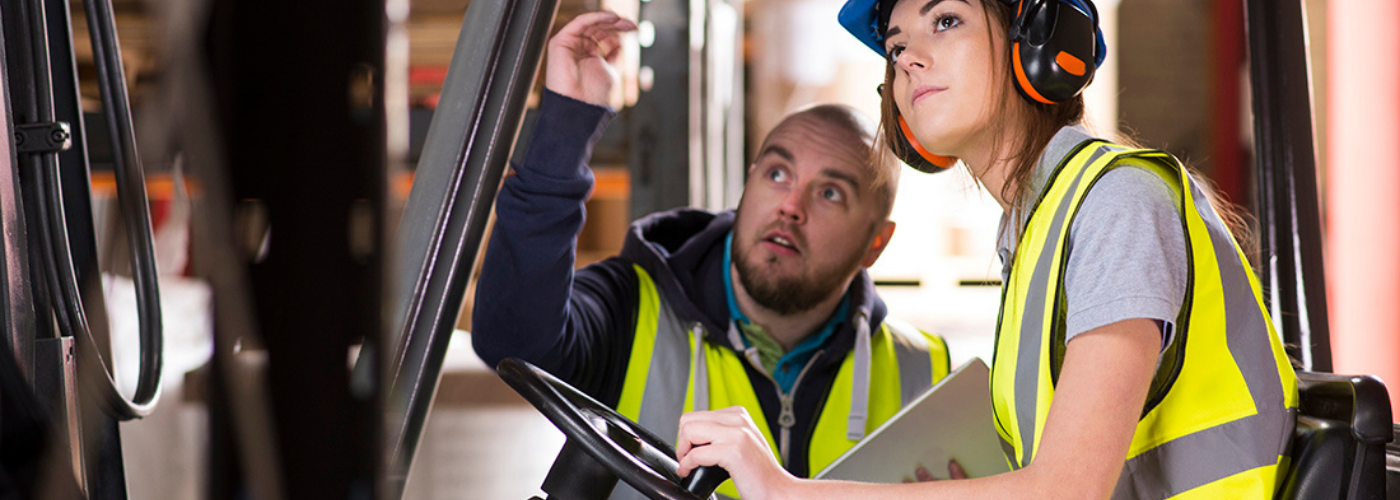 jeune femme sur un chariot de manutention avec un formateur