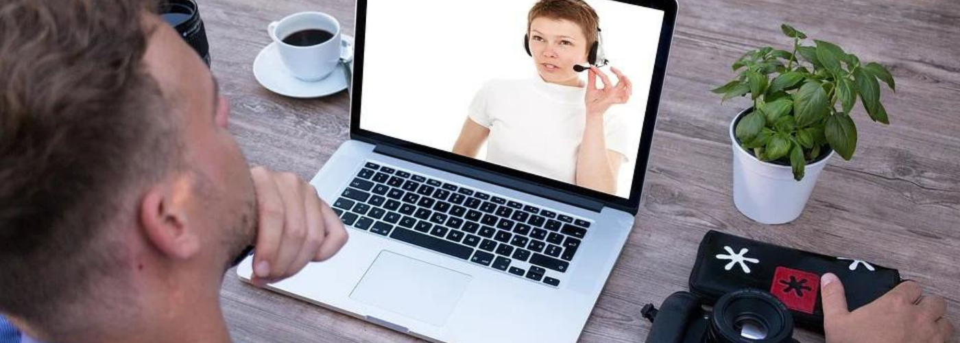 Formation à distance homme devant son ordinateur écoutant une femme