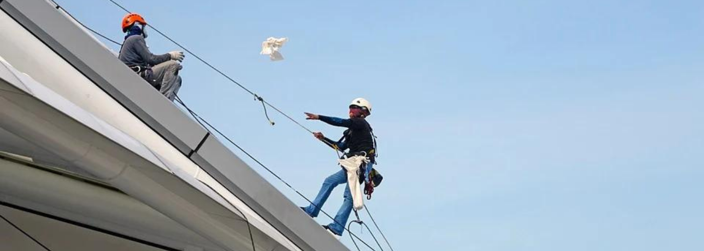 2 hommes portant des harnais au dessus d'un toit