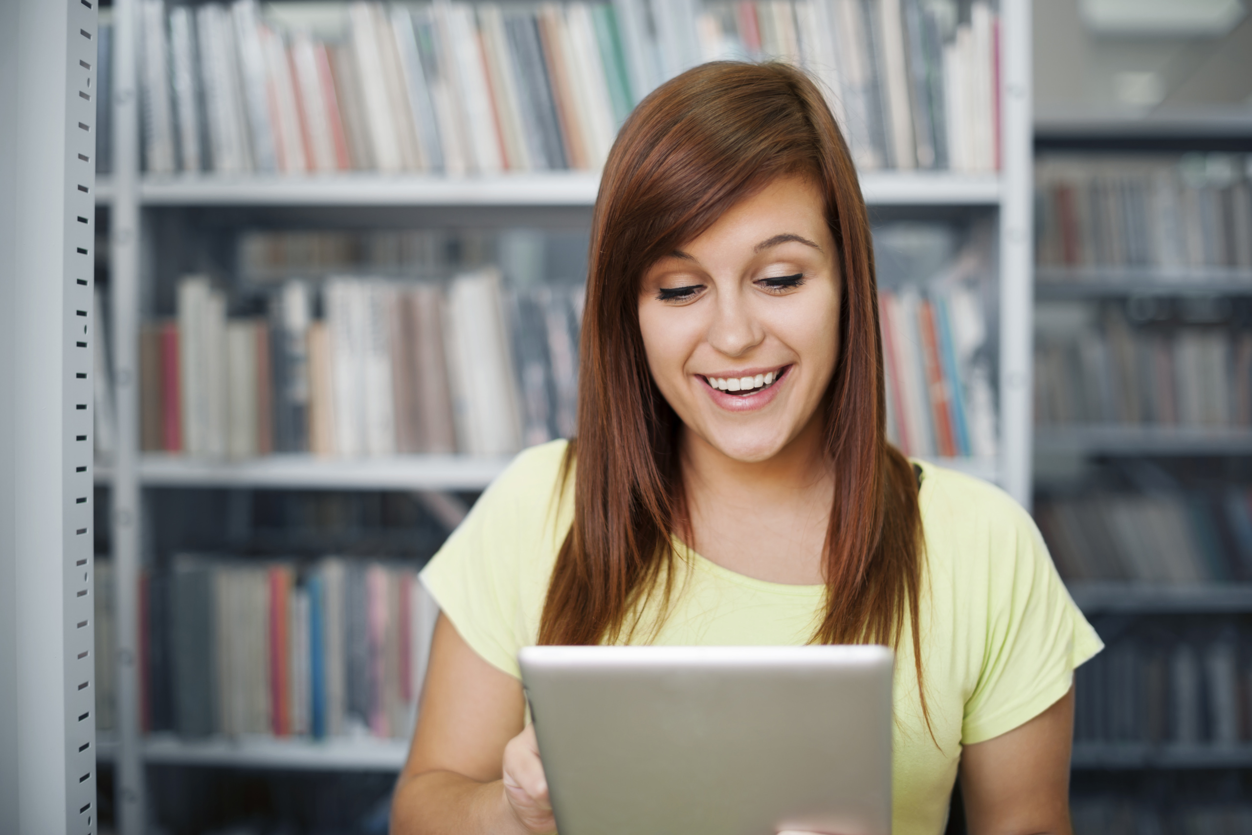 Photo d\'une femme souriante qui regarde le livre blanc qu\'elle a téléchargé sur sa tablette