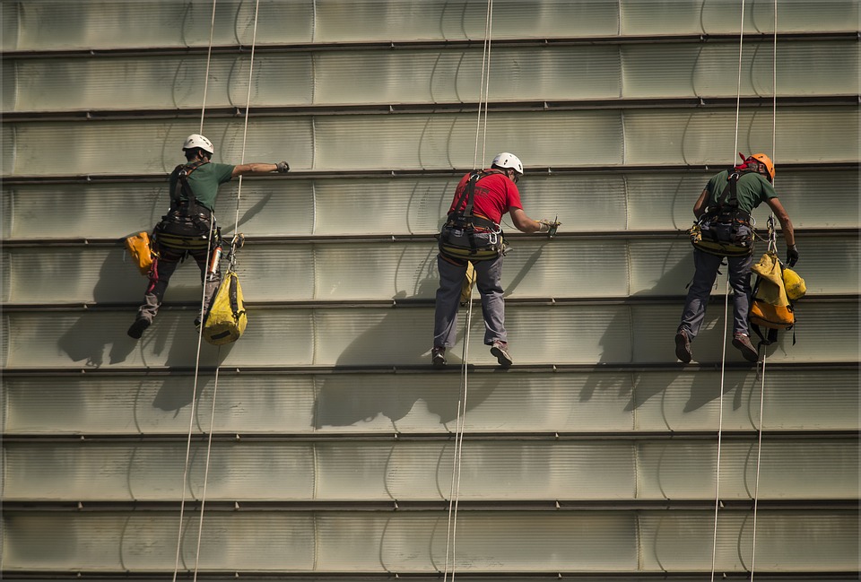 Trois hommes accrochés à un harnais font du travail en hauteur